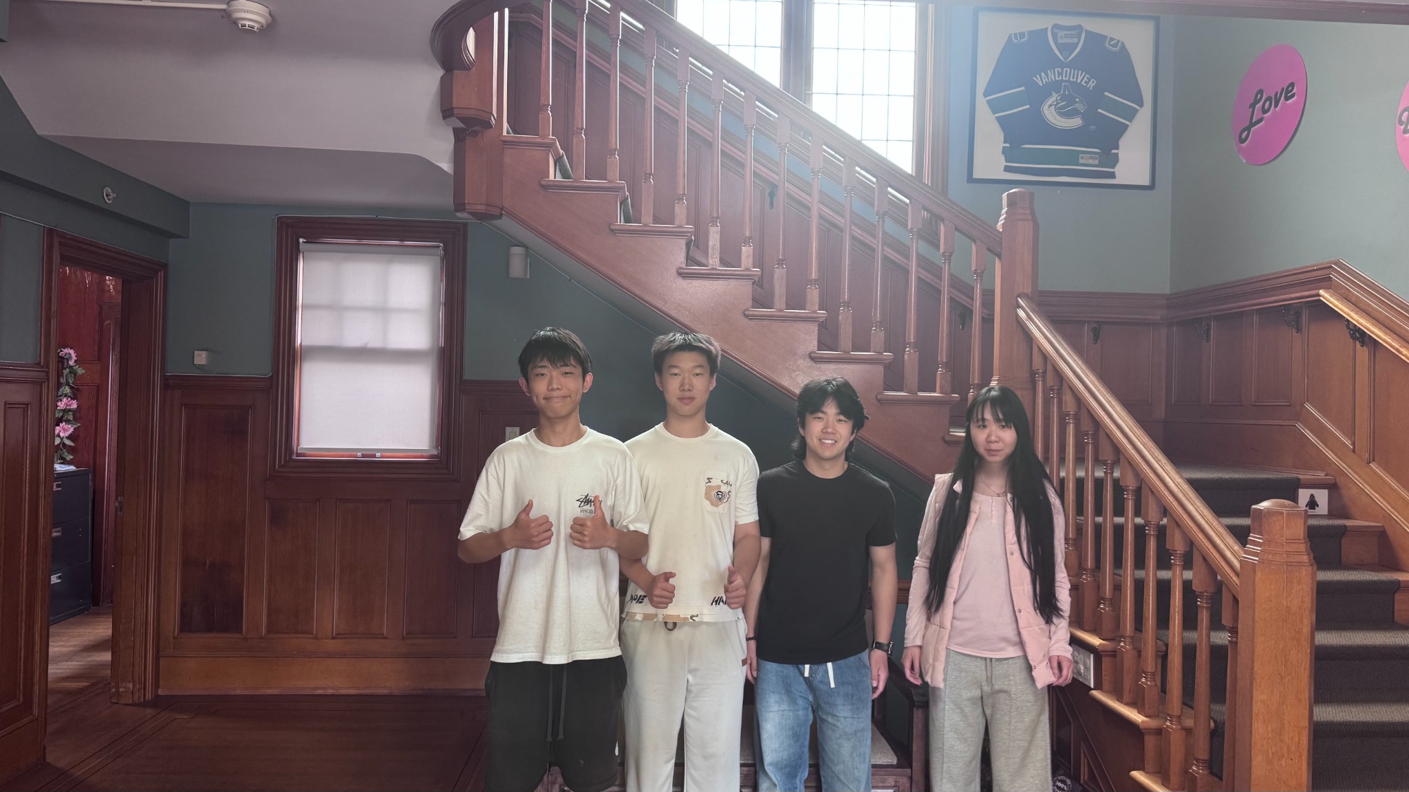 Four SecondShelf team members standing together beside a wooden staircase